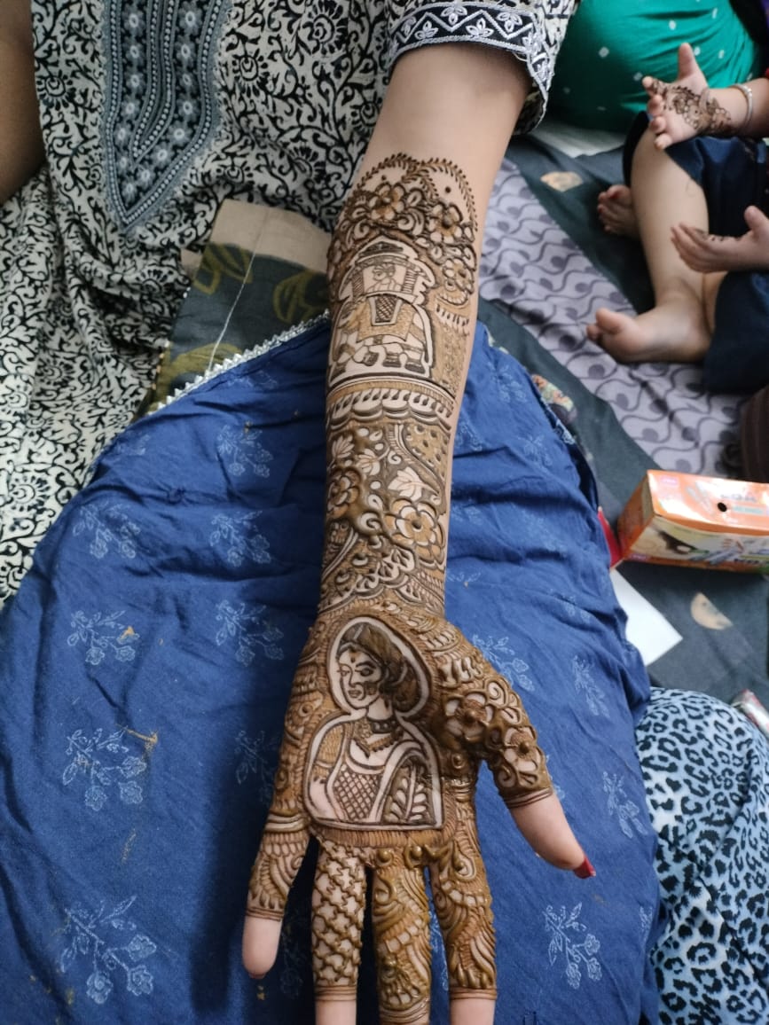 Traditional bridal mehndi with dulhan portrait and doli motif on hand and arm