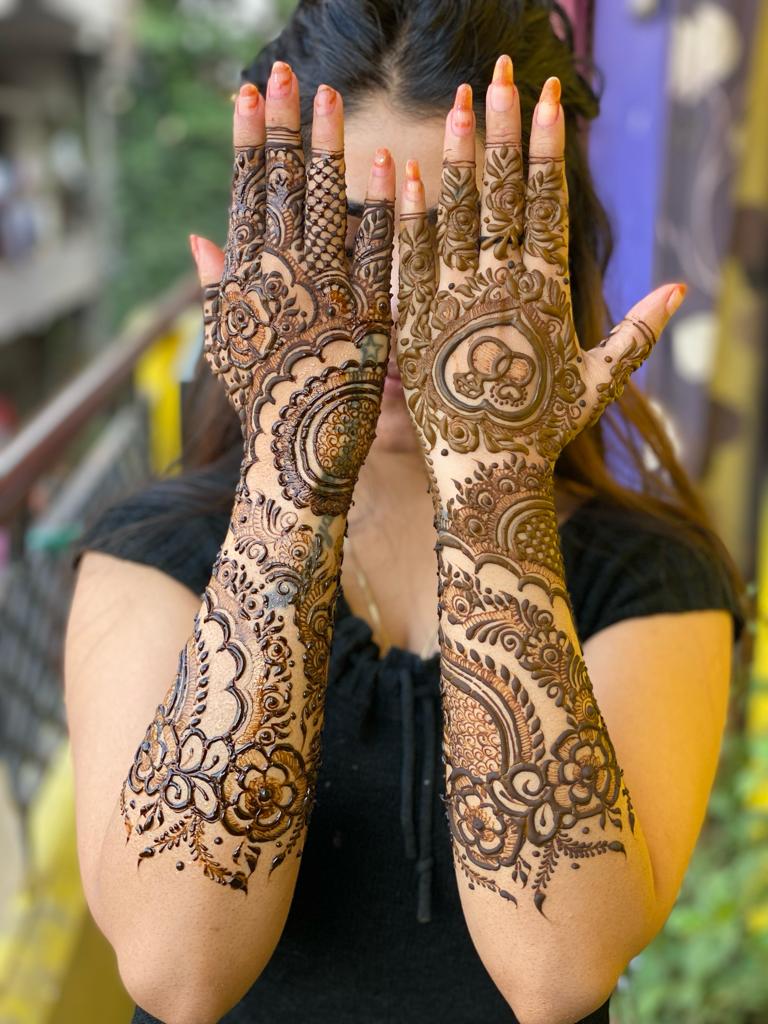 Bride showing full-arm bridal mehndi with roses and fine shading